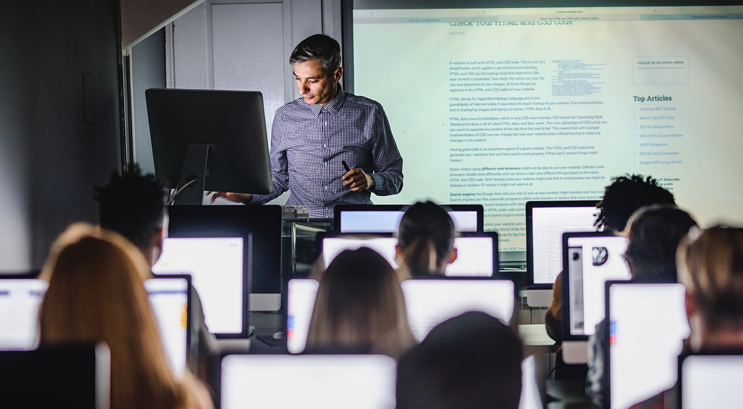 A professor delivers a presentation to a group of students in a classroom setting.